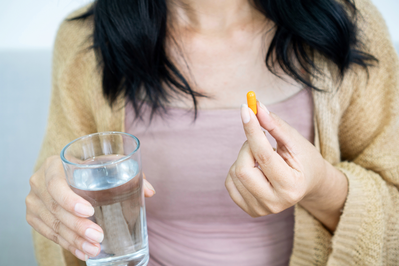 woman holding pill and glass of water