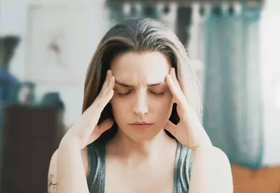 woman closing eyes and holding head