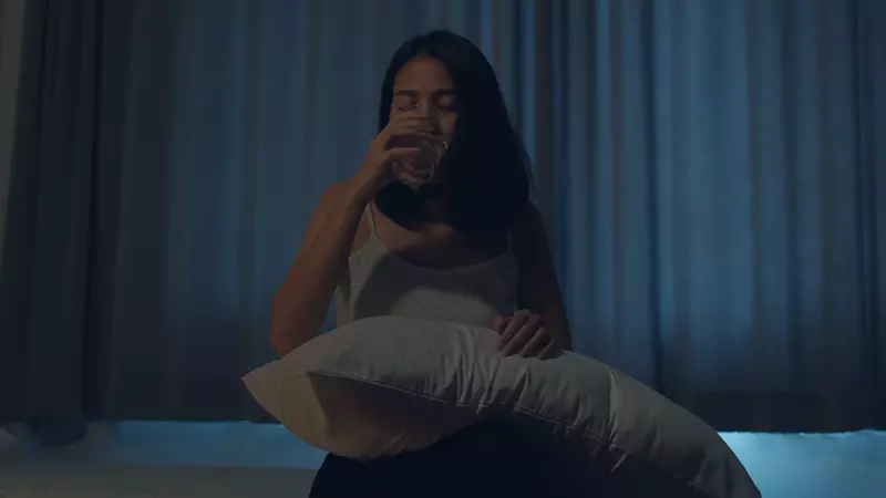 woman drinking water in bed at night