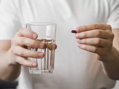 person holding water and pill